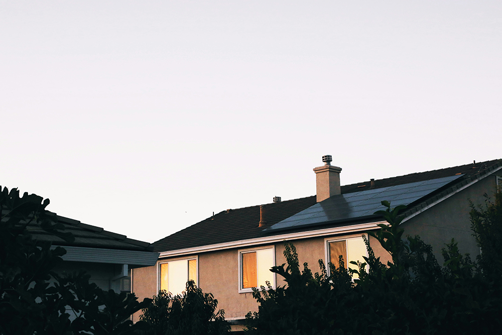 Solar panels on a home, with lights on in upstairs window