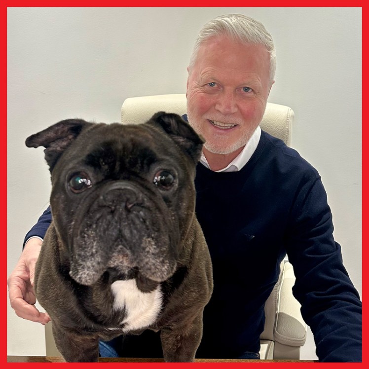 Arthur the dog is in the foreground, with a smiling owner sat behind him