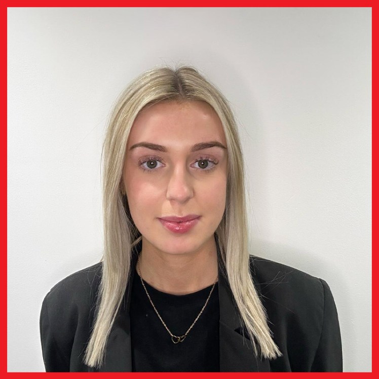 A headshot of a lady with long blonde hair and a black top on a white background
