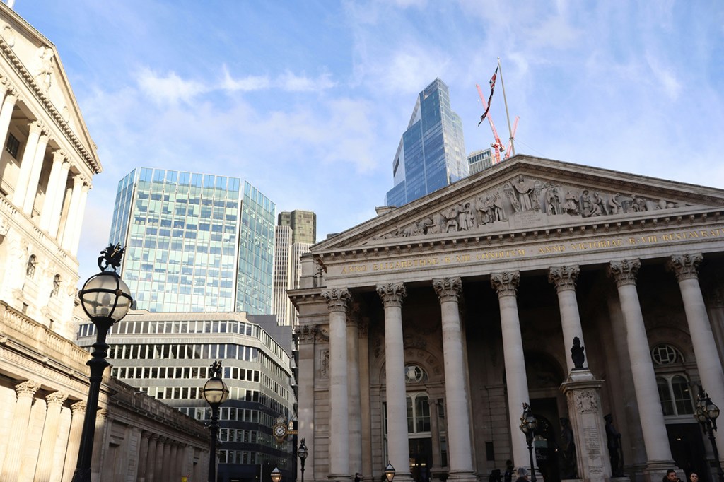 View of outside the Bank of England building in London on the right, with high-rise buildings in the background