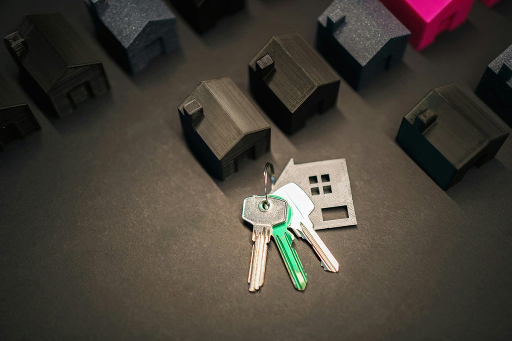 Wooden models of homes on a table with a bunch of keys with a house keyring