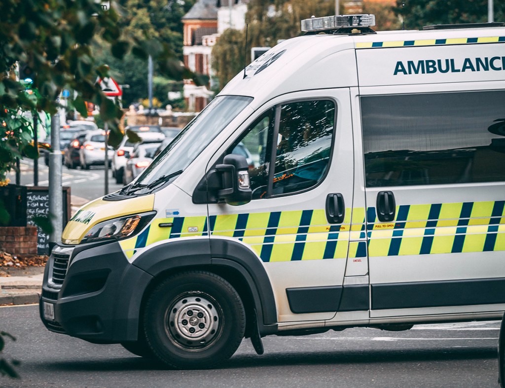 The front half of an ambulance parked on a road from right to left.