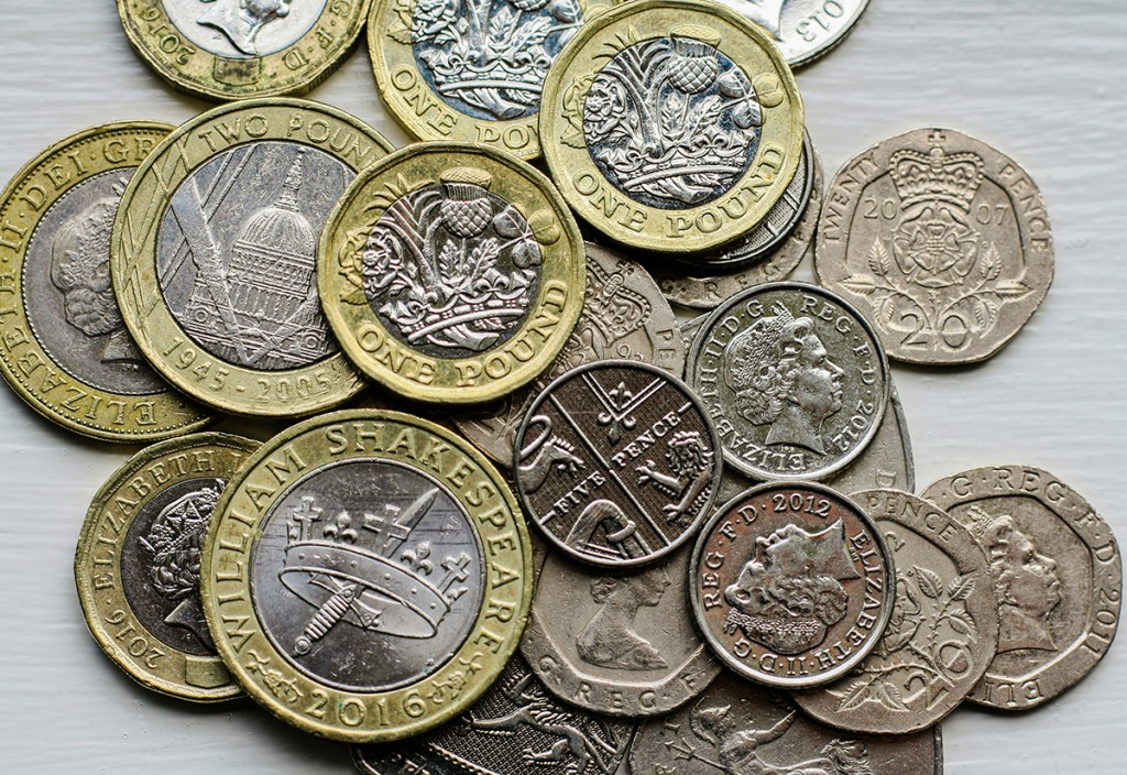 A pile of British coins on a grey background
