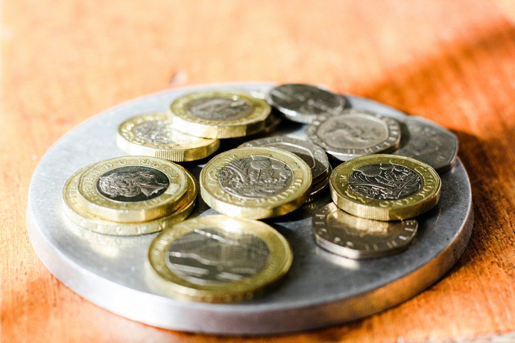 A silver tray of coins on a wooden table