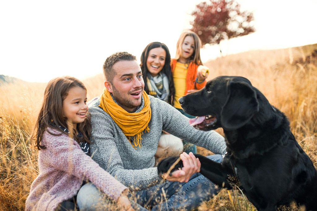 A family of mum, dad and two children with a black dog